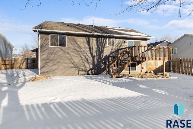 snow covered rear of property featuring stairs, fence, and a wooden deck