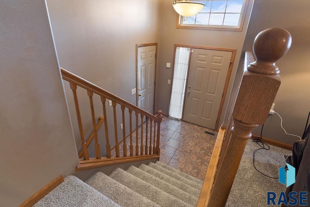 tiled foyer entrance featuring baseboards, stairway, and a towering ceiling