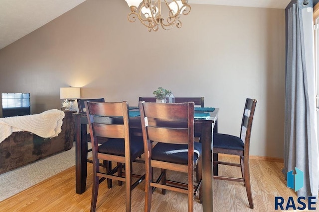 dining space featuring lofted ceiling, light wood-type flooring, a chandelier, and baseboards