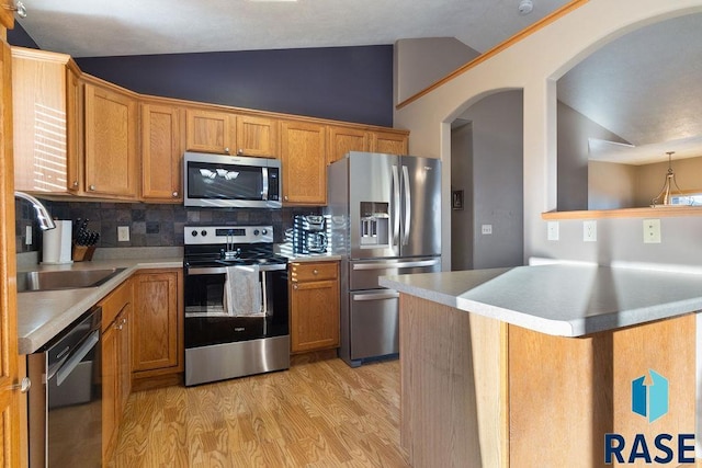 kitchen featuring lofted ceiling, a peninsula, stainless steel appliances, light countertops, and a sink