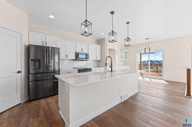 kitchen featuring stainless steel appliances, light countertops, white cabinetry, and an island with sink