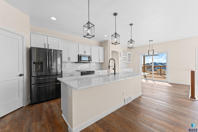 kitchen with pendant lighting, stainless steel appliances, an island with sink, and white cabinets