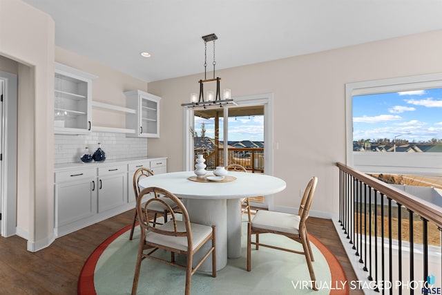 dining space with dark wood-type flooring, recessed lighting, a notable chandelier, and baseboards