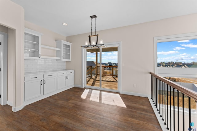 kitchen with glass insert cabinets, light countertops, white cabinets, and dark wood-type flooring