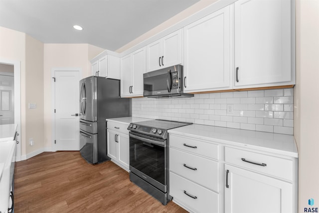 kitchen with decorative backsplash, appliances with stainless steel finishes, wood finished floors, white cabinetry, and recessed lighting