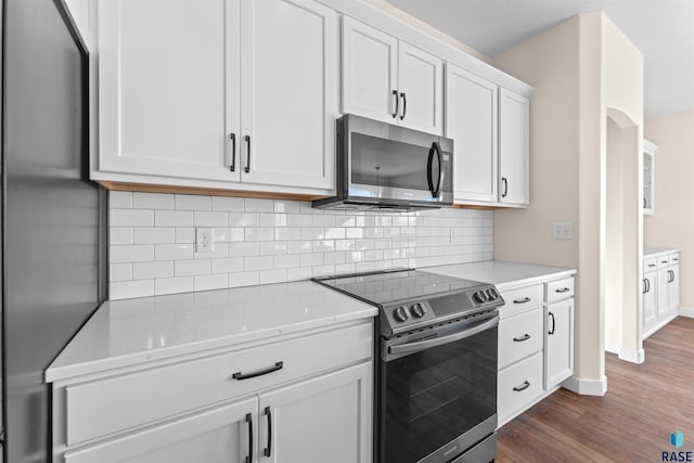 kitchen featuring light stone counters, stainless steel appliances, dark wood-type flooring, white cabinets, and decorative backsplash