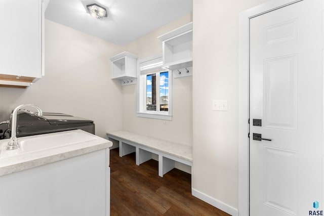 clothes washing area featuring dark wood-style floors, a sink, cabinet space, and baseboards