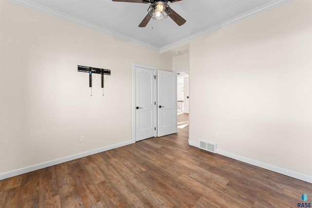 empty room featuring ornamental molding, wood finished floors, visible vents, and baseboards