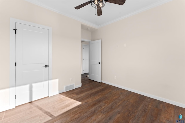 unfurnished bedroom with dark wood-style floors, baseboards, visible vents, and ornamental molding