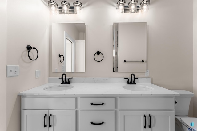 bathroom featuring toilet, double vanity, and a sink