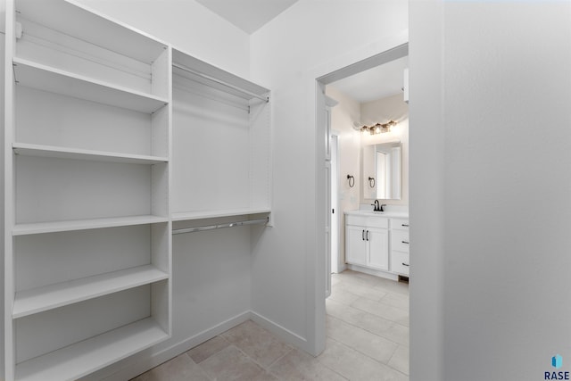 spacious closet featuring a sink and light tile patterned floors