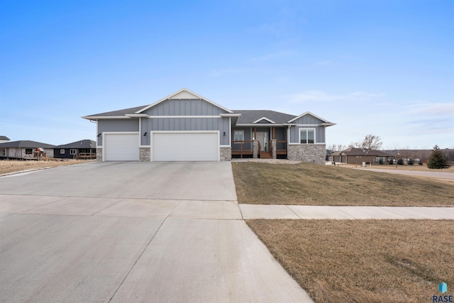 view of front of property with an attached garage, stone siding, driveway, board and batten siding, and a front yard