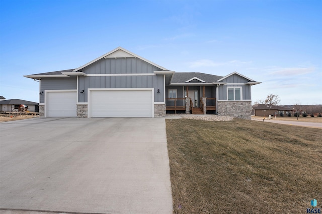 view of front of home with stone siding, a front lawn, board and batten siding, and an attached garage