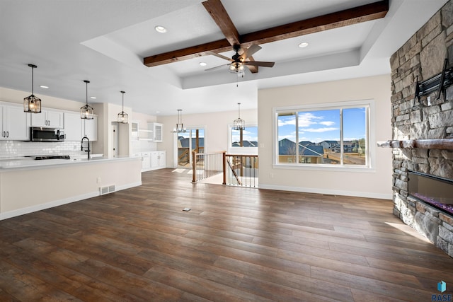 unfurnished living room featuring dark wood-style flooring, a fireplace, a sink, and a wealth of natural light