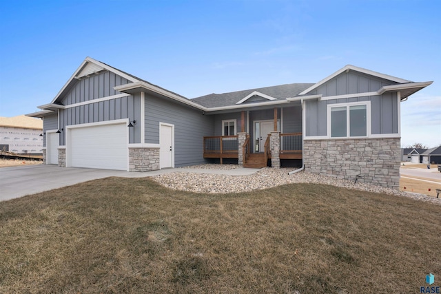 view of front facade with board and batten siding, stone siding, an attached garage, and a front lawn