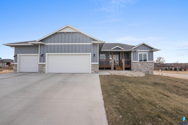 view of front of house with an attached garage, concrete driveway, stone siding, board and batten siding, and a front yard