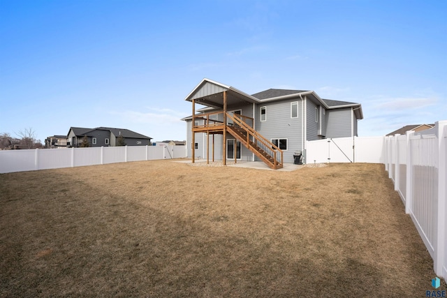 rear view of house featuring a fenced backyard, stairway, and a lawn