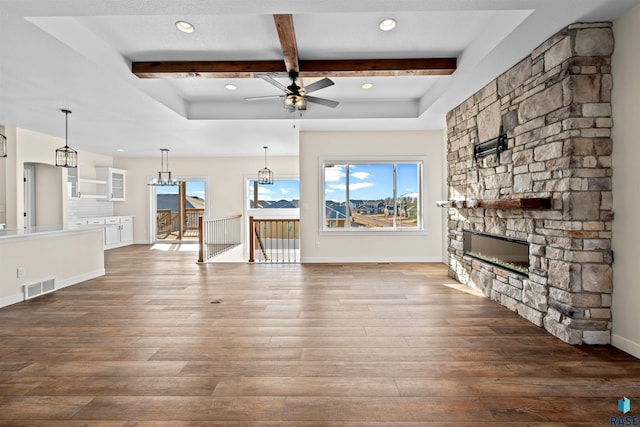 unfurnished living room featuring baseboards, visible vents, wood finished floors, beamed ceiling, and a fireplace