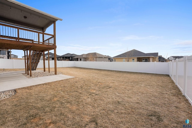 view of yard with a residential view, a fenced backyard, and stairs