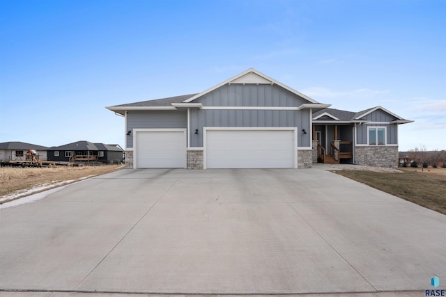 view of front facade featuring a shingled roof, concrete driveway, board and batten siding, a garage, and stone siding