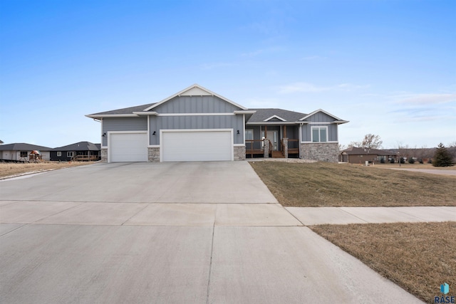 view of front of property featuring a garage, driveway, stone siding, board and batten siding, and a front yard