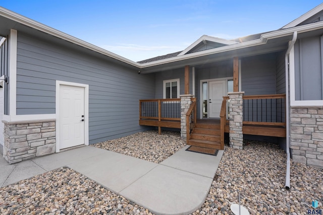 doorway to property with stone siding and covered porch