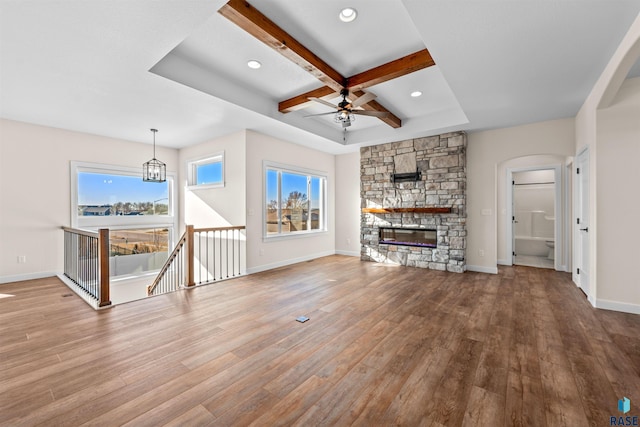 unfurnished living room with coffered ceiling, baseboards, a fireplace, and light wood finished floors