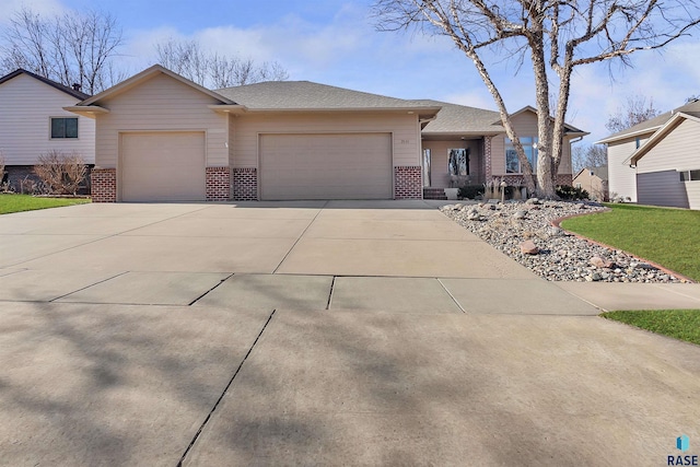 ranch-style home featuring an attached garage, a shingled roof, concrete driveway, and brick siding