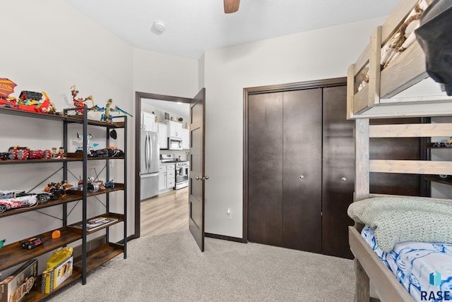 bedroom featuring ceiling fan, light colored carpet, a closet, and freestanding refrigerator