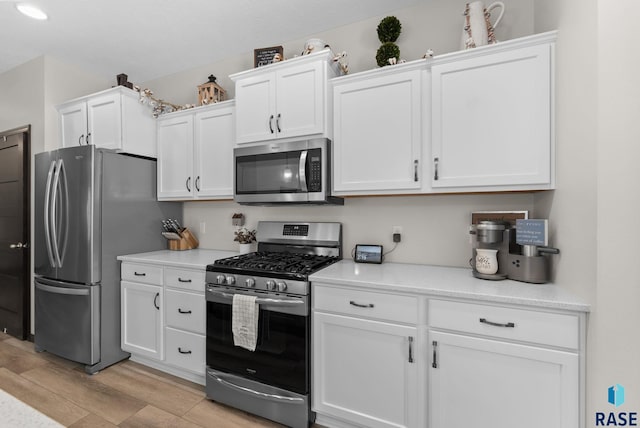 kitchen with stainless steel appliances, light wood-type flooring, light countertops, and white cabinets