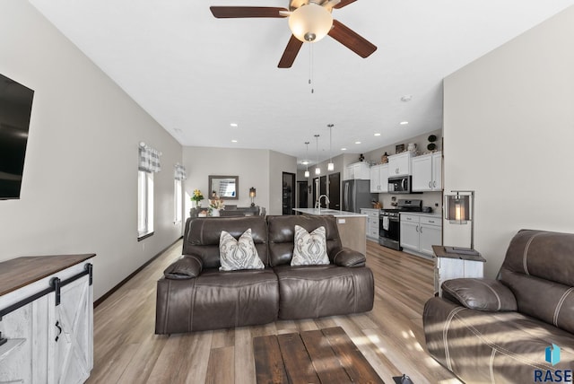 living area featuring light wood finished floors, a ceiling fan, and recessed lighting