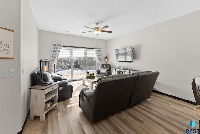 living room with a ceiling fan, light wood-style flooring, and baseboards