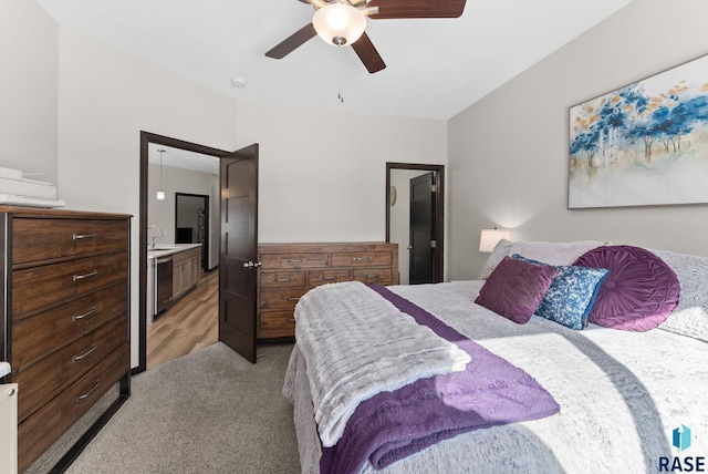 bedroom with a sink, ceiling fan, connected bathroom, and light colored carpet