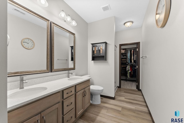 bathroom featuring visible vents, a sink, a spacious closet, and double vanity