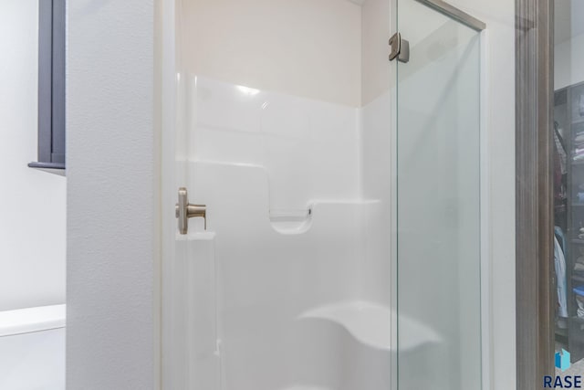 full bath featuring a stall shower and toilet