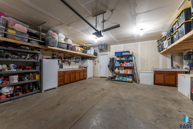 garage featuring fridge, a garage door opener, and freestanding refrigerator