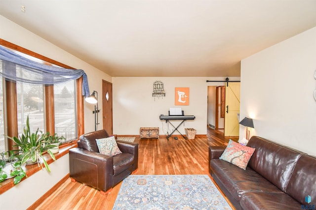 living area with wood finished floors, baseboards, and a barn door