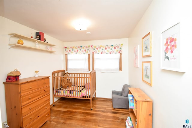 bedroom with a crib and wood finished floors