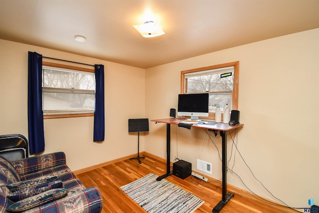 home office with visible vents, plenty of natural light, baseboards, and wood finished floors