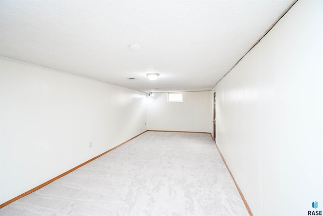 spare room with light carpet, a textured ceiling, and baseboards