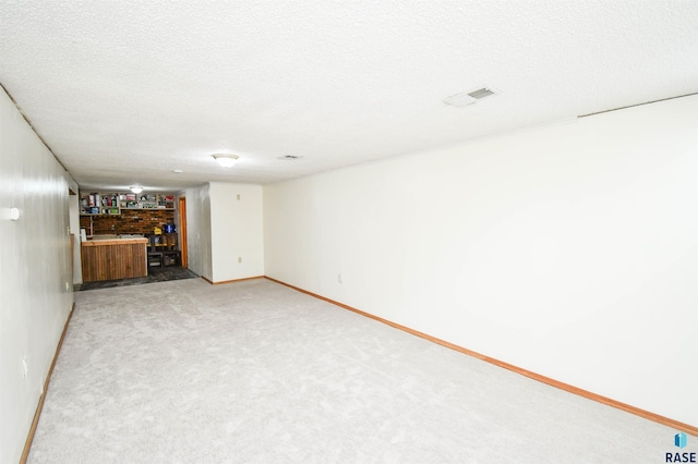 unfurnished living room with a textured ceiling, carpet floors, visible vents, and baseboards