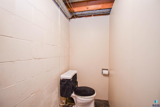 bathroom with concrete block wall and toilet