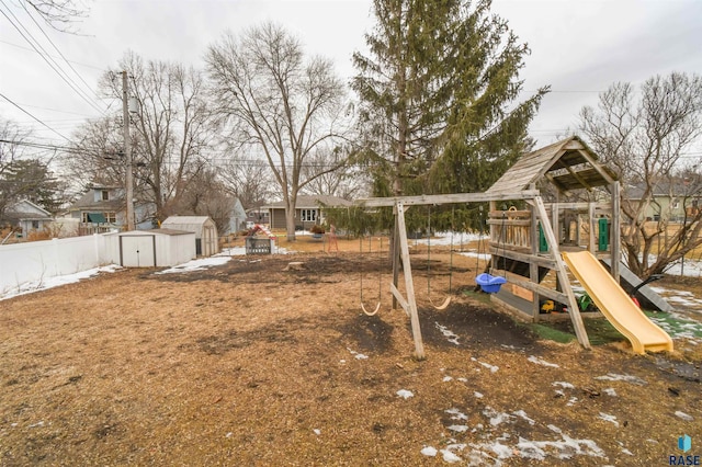 view of jungle gym with a shed, fence, and an outbuilding