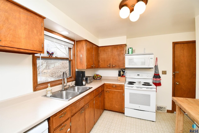 kitchen with white appliances, light countertops, a sink, and light floors