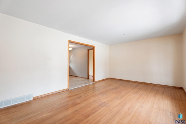 empty room with light wood-type flooring, visible vents, and baseboards