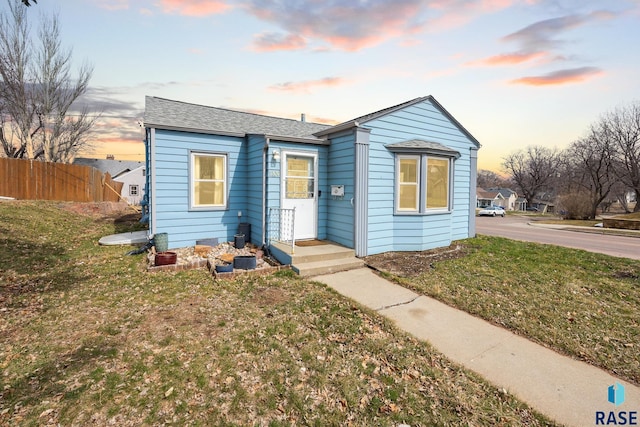 bungalow-style house with a lawn and fence