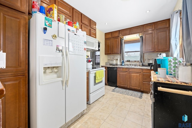 kitchen with light tile patterned floors, white appliances, and brown cabinetry