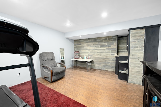 exercise room featuring an accent wall, wood walls, wood finished floors, and recessed lighting