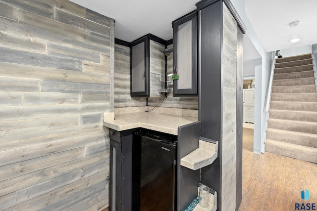 bar with stairs, fridge, and light wood-style floors