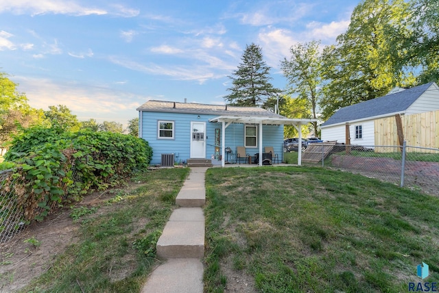 view of front of home with entry steps, a fenced backyard, central AC unit, and a front yard